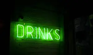 Zielony neon "DRINKS" na ceglanej ścianie. Czas na drinka, jakim alkoholem jesteś?
