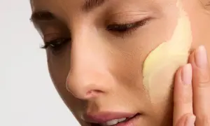 Application d'une crème riche en céramides pour une peau éclatante. Les doigts doux étalent la texture onctueuse.