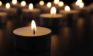 Płonące świece w ciemności, symbolizujące żałobę i pamięć.