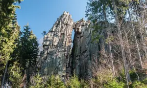 Skalny most na rudawych janowickich szlakach, otoczony drzewami.