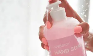 Dłoń z różowymi paznokciami trzyma różowy płyn do mycia rąk Swederm. Woda spływa po butelce, a na etykiecie widać napis "HAND SOAP". Czy gliceryna jest szkodliwa? Ten produkt zawiera jej wysoki poziom.