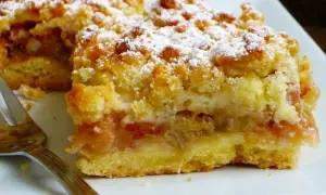 Kruche ciasto z rabarbarem i kruszonką, posypane cukrem pudrem. Idealne na letnie popołudnie.