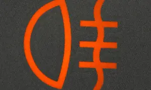 Pomarańczowy symbol świateł mijania na ciemnoszarym tle. Ikona przedstawia wiązkę światła skierowaną w dół i trzy poziome linie.