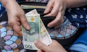 Dwie dłonie przekazują sobie banknot 100 zł. Może to być symbol wsparcia finansowego, np. renta wdowia, choć jej limit jest nieznany.