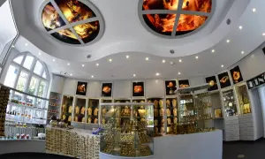 Wnętrze muzeum bursztynu Kołobrzeg. W gablotach błyszczą złote ozdoby, a na suficie zdobią okrągłe panele z bursztynu.