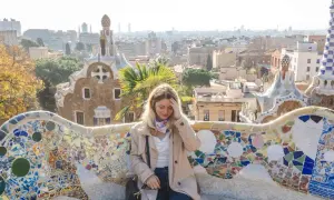 Frau sitzt auf einer bunten Mosaikbank im Park Güell, mit Blick auf Barcelona. Tolle Barcelona Tipps für deinen Besuch!