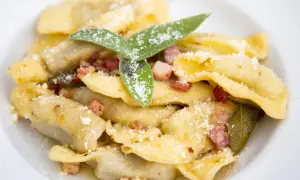 Un piatto di casoncelli alla bergamasca, ripieni e conditi con burro, salvia e pancetta croccante, spolverati di parmigiano.