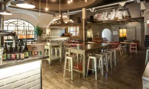 Interno del birrificio Legnano con tavoli, sgabelli e birre in bottiglia sul bancone.
