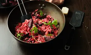 Un délicieux risotto betterave, garni de roquette fraîche et de copeaux de parmesan, prêt à être dégusté.