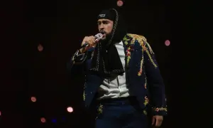 Bad Bunny koncert: artysta w ozdobnej marynarce i czapce z napisem "Puerto Rico" śpiewa do mikrofonu na tle rozmytych świateł.