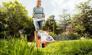 Mujer cortando césped con cortacésped eléctrico. Consejos para cortar el césped: mantén la cuchilla afilada y la altura adecuada.