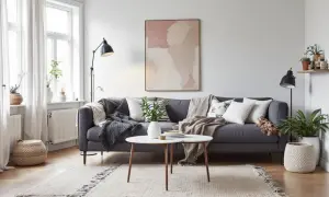 En grå soffa med kuddar och plädar, ett runt soffbord och en matta. En tavla med abstrakt mönster ger en känsla av exotisk inredning.