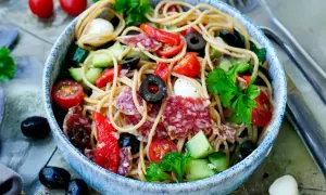 Spaghetti-Salat mit Salami, Tomaten, Oliven und Mozzarella. Ein einfach und schnell zubereitetes Gericht, perfekt für heiße Tage.