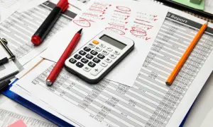 Calculatrice, stylos et feuilles de calcul. Préparation des comptes pour la taxe sur les salaires 2024.