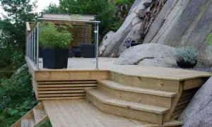 En nybyggd trappa på berg ger tillgång till en altan med sittgrupp och grillplats.