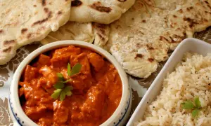 Pyszny butter chicken z chlebkiem naan i ryżem. Idealny posiłek dla miłośników indyjskich smaków.