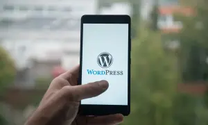 Dłoń trzyma smartfon z logo WordPress. Idealne narzędzie dla webmasterów do zarządzania stronami.