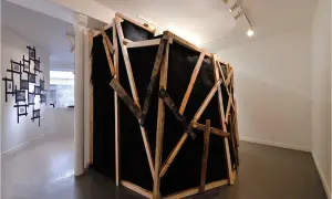 Instalacja artystyczna z czarnym materiałem i drewnianą konstrukcją, nawiązująca do prac Miroslava Tichego.