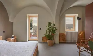 Interno moderno con soffitti a volta, letto, pianta e vista panoramica. Sembra una di quelle case a un euro che diventano gioielli.