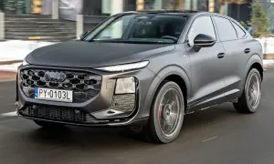 Nowe Audi Q3 w matowym, grafitowym kolorze sunie po drodze, prezentując swój sportowy charakter i nowoczesny design.