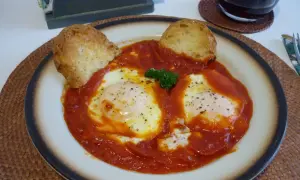 Uova in trippa marchigiana, un piatto saporito con uova cotte nel sugo di pomodoro, guarnito con pane tostato e prezzemolo.