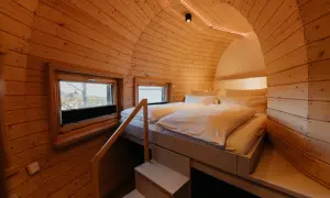 Gemütliches Holz-Schlafzimmer mit Doppelbett und Fenstern, ideal für einen erholsamen Aufenthalt in Bad Harzburg.