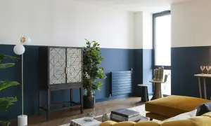 Soggiorno moderno con pareti bicolore blu e bianche, un mobile etnico e un divano giallo ocra. Idee pareti colorate particolari per un look audace.