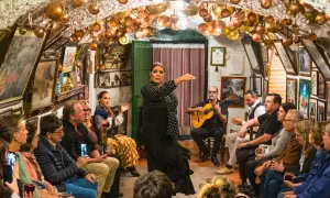 Una bailaora de flamenco, con un guitarrista y público, en un local decorado con cobre. ¡Gracias en flamenco!