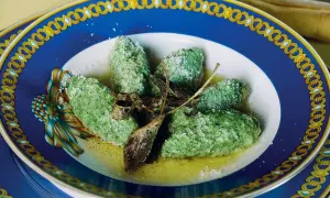 Strangolapreti alla trentina, verdi e saporiti, serviti in un piatto elegante con burro fuso e salvia croccante.