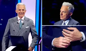 Hubert Urbański w eleganckim garniturze, z widocznym tatuażem na dłoni.