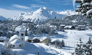 Winteridylle in der Schweiz: verschneite Berge, ein Dorf mit Kirche und Häusern, umgeben von Tannen.
