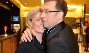 Maciej Orłoś z żoną, uśmiechnięci, w eleganckich strojach, w intymnym uścisku.