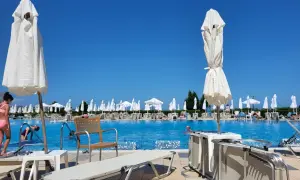 Basen hotelowy z leżakami i parasolami pod błękitnym niebem.