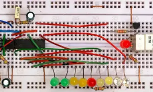 Układ na płytce stykowej z układem scalonym, diodami LED, przyciskiem i przekaźnikiem. To jest projekt z użyciem multipleksera.