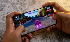 Ręce trzymają smartfon, na którym gra wyścigowa. Idealny telefon do 2500 zł poradzi sobie z taką grafiką.