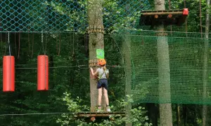Dziecko w kasku na parku linowym w Hajnówce. Wspaniałe atrakcje dla dzieci w lesie.