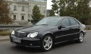 Czarny Mercedes W203 w ruchu, świeci się jedna żarówka mijania, sugerując potrzebę wymiany.