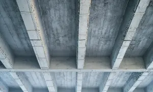 Widok od spodu na betonowy strop z widocznymi belkami i płytami.