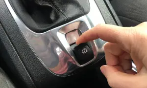Dito, un dito preme il pulsante del freno a mano elettronico, simbolo di sicurezza e modernità.