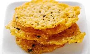 Krispiga, gyllene pasta chips med örter och peppar staplade på en vit tallrik. Perfekt som tilltugg!