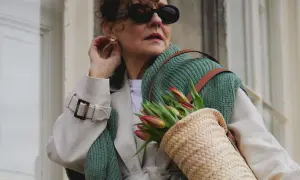 Elegancka kobieta w okularach i płaszczu, z koszykiem pełnym tulipanów. Uosobienie stylu francuskiego w modzie damskiej.