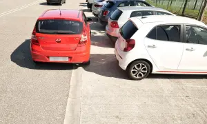 Coches aparcados en batería, un rojo y un blanco, junto a una acera.