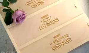 Drewniane pudełko na wino z grawerem "A Quiet Night Together", "A Night of Celebration", "The Night of Your Anniversary" i różową różą.