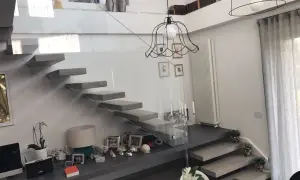 Scala interna moderna con gradini a sbalzo e parapetto in vetro. Un modo elegante per come abbellire una scala interna con decorazioni e piante.