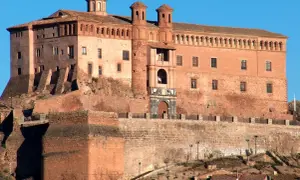 Imponente castillo Zaragoza, con sus torres y cúpulas, se alza sobre una colina rocosa, vigilando el paisaje.