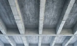 Widok od dołu na betonowy strop z belkami. Obliczenia obciążenia stropu żelbetowego na m2 są kluczowe dla bezpieczeństwa konstrukcji.