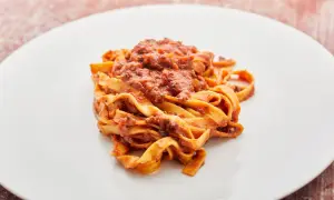 Breite Bandnudeln mit einer herzhaften vegetarischen Bolognese-Sauce auf einem weißen Teller.
