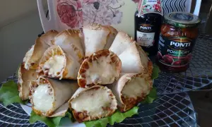 Pyszne rożki z tortilli z mięsem mielonym i ciągnącym się serem, podane na liściach sałaty. Obok butelka sosu balsamicznego i słoik pomidorów.