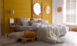 Une chambre d'adulte lumineuse avec un mur jaune vif, un lit douillet et une décoration murale en rotin.