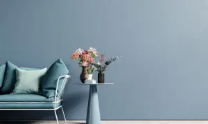 Divano blu e tavolino con fiori su muro azzurro, un esempio di moderni stili di pittura per interni.
